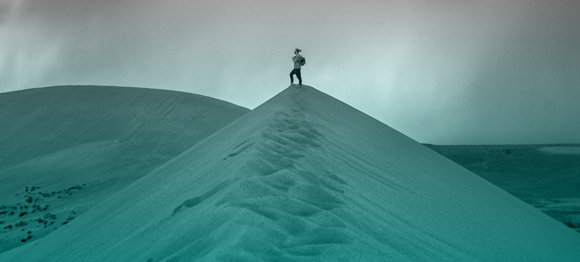 Backpacker standing on top of sand dune
